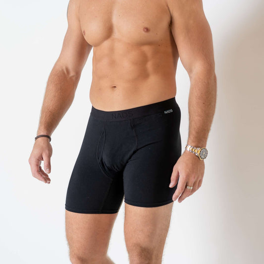Man wearing  Black Boxer Briefs standing in a white studio room from neck to knees.